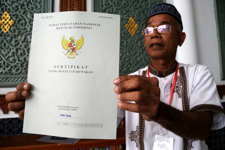 Seorang penerima memperlihatkan sertifikat tanah wakaf masjid, mushola, dan pasantren yang diserahkan Presiden Joko Widodo seusai melaksanakan ibadah Jumat di Banda Aceh, Aceh.