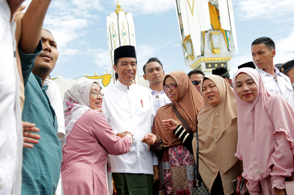 Warga berfoto dengan Presiden Joko Widodo setelah penyerahan sertifikat tanah wakaf kepada pengurus masjid, mushola dan pasantren seusai melaksanakan ibadah Jumat di Banda Aceh. Presiden berada di Provinsi Aceh untuk melakukan kunjungan kerja sejak 13-14 Desember 2018.
