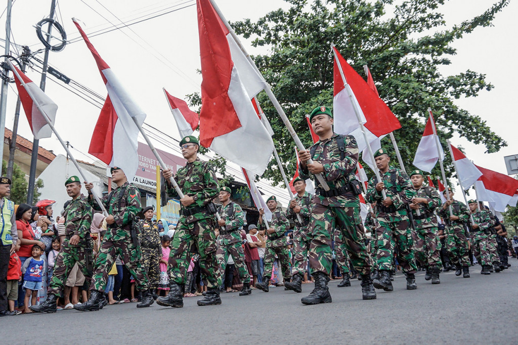 Anggota TNI membawa bendera merah putih saat mengikuti kirab Pajang Jimat saat peringatan Maulid Nabi dalam rangkaian kegiatan Kanzus Sholawat di Pekalongan, Jawa Tengah.