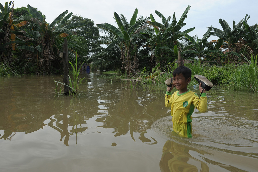 Pelajar menerobos genangan banjir luapan Sungai Batanghari di Legok, Telanaipura.