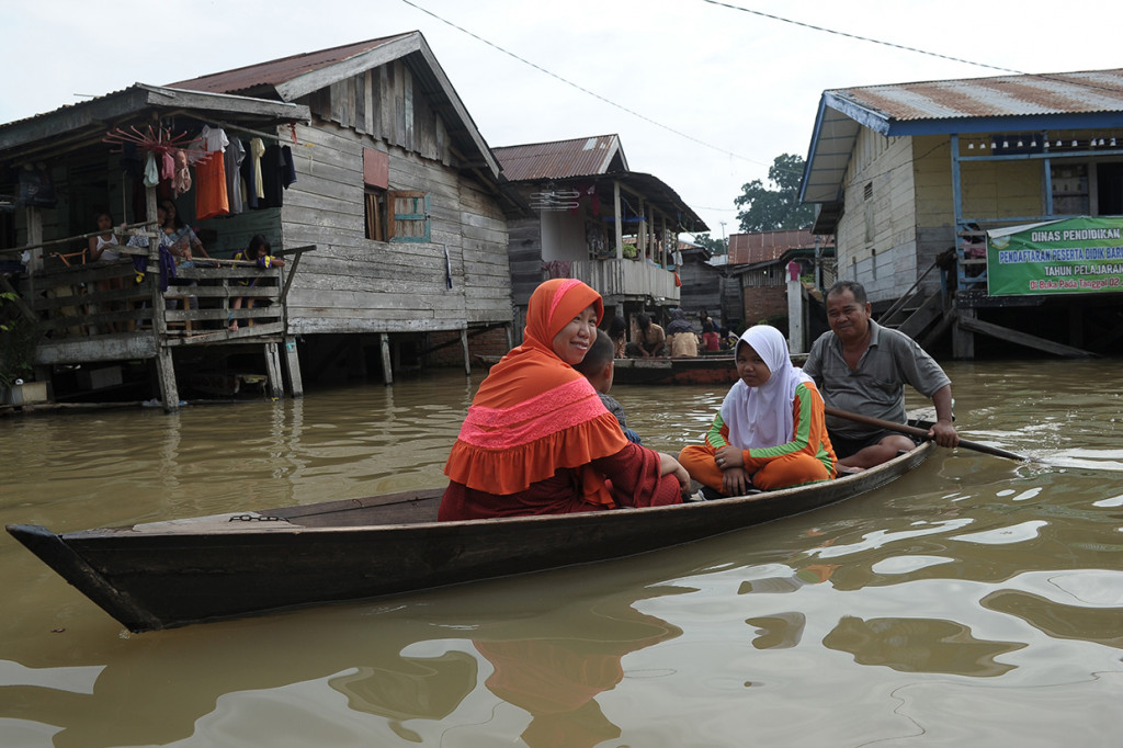Orang tua murid menjemput anaknya menggunakan perahu dari sekolah yang tergenang banjir luapan Sungai Batanghari di Legok, Telanaipura, Jambi.