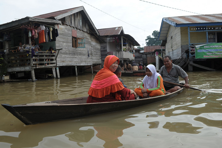 Orang tua murid menjemput anaknya menggunakan perahu dari sekolah yang tergenang banjir luapan Sungai Batanghari di Legok, Telanaipura, Jambi.