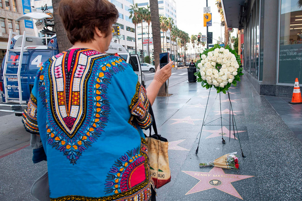 Seorang pejalan kaki mengabadikan karangan bunga yang diletakkan di bintang Penny Marshall di Hollywood Walk of Fame, Hollywood, California, Selasa, 18 Desember waktu setempat. Marshall meninggal di kediamannya Hollywood Hills pada Senin, 17 Desember karena komplikasi diabetes.
