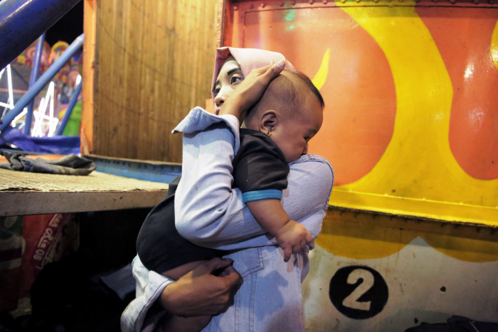 Di sela waktu istirahatnya, Devi meninabobokkan putrinya yang tidurnya terganggu bisingnya suara sepeda motor. 