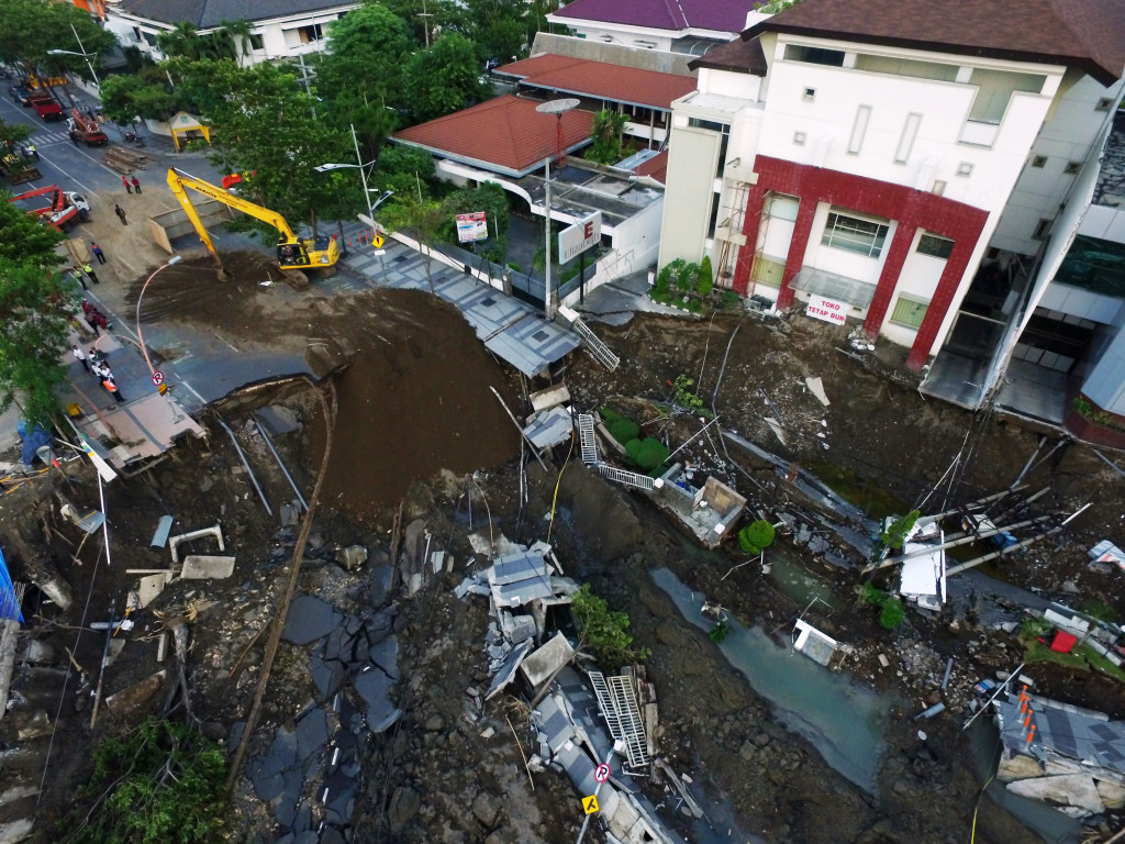 Kegiatan pengurukan di lokasi ruas jalan yang ambles. Dua alat berat Dinas Pekerjaan Umum Bina Marga dan Pematusan Kota Surabaya menguruknya dengan pasir, tanah dan batu. 