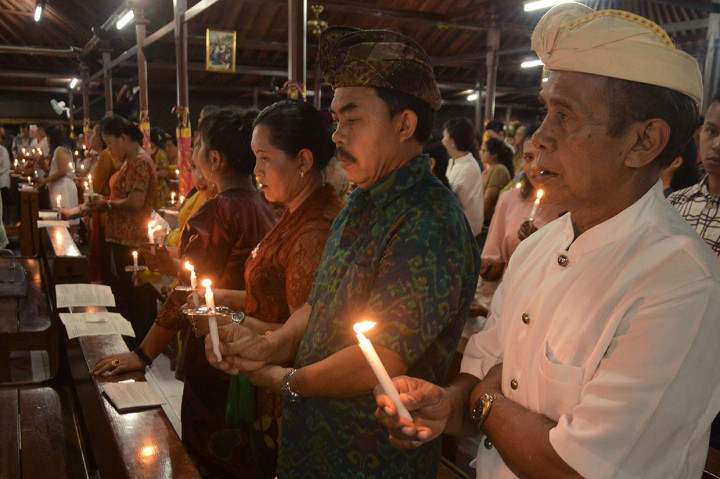Umat Katolik mengikuti prosesi Misa Malam Natal di Gereja Katolik Tritunggal Mahakudus, Desa Tuka, Badung, Bali. Perayaan Natal di gereja tersebut menggunakan nuansa budaya Bali, seperti jemaat yang mengenakan busana adat Bali, penggunaan bahasa Bali, dan ornamen gereja berarsitektur tradisional Bali. Antara Foto/Fikri Yusuf