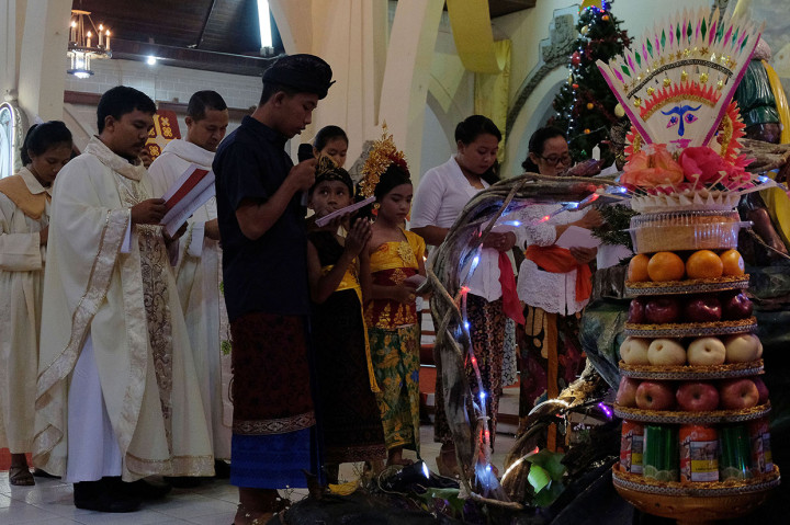 Sejumlah umat Katolik berbusana adat Bali memanjatkan doa saat misa malam Natal di Gereja Katolik Hati Kudus Yesus Palasari, Jembrana, Bali. Misa malam Natal dengan berpakaian adat Bali merupakan tradisi umat Katolik di Desa Palasari sebagai simbol akulturasi. Antara Foto/Nyoman Hendra Wibowo