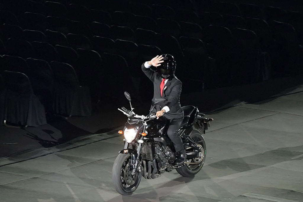 Presiden Joko Widodo membuat kejutan di pembukaan Asian Games 2018. 'Jokowi' naik moge hitam ke lokasi pembukaan yang digelar di Stadion Gelora Bung Karno (GBK) Senayan, Jakarta, 19 Agustus 2018. Aksi ini menjadi ‘debat kusir’ bertendensi politik yang cukup panas di media sosial hingga berhari-hari kemudian. INASGOC/Antara Foto/Dhoni Setiawan