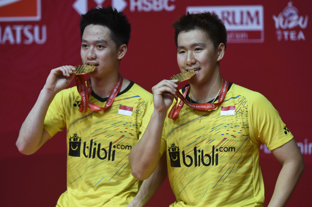 Ganda putra Indonesia Kevin Sanjaya Sukamuljo (kiri) dan Marcus Fernaldi Gideon menggigit medali emas seusai mengalahkan ganda putra Tiongkok Li Junhui dan Liu Yuchen pada babak final Indonesia Masters 2018 di Istora Senayan, Jakarta, Minggu, 28 Januari. Kevin/Marcus tampil sebagai juara setelah menang dengan skor 11-21, 21-10, dan 21-16. Ganda putra terbaik dunia tersebut sepanjang 2018 telah mengoleksi sembilan gelar juara, ditambah medali emas Asian Games. Antara Foto/Hafidz Mubarak A 