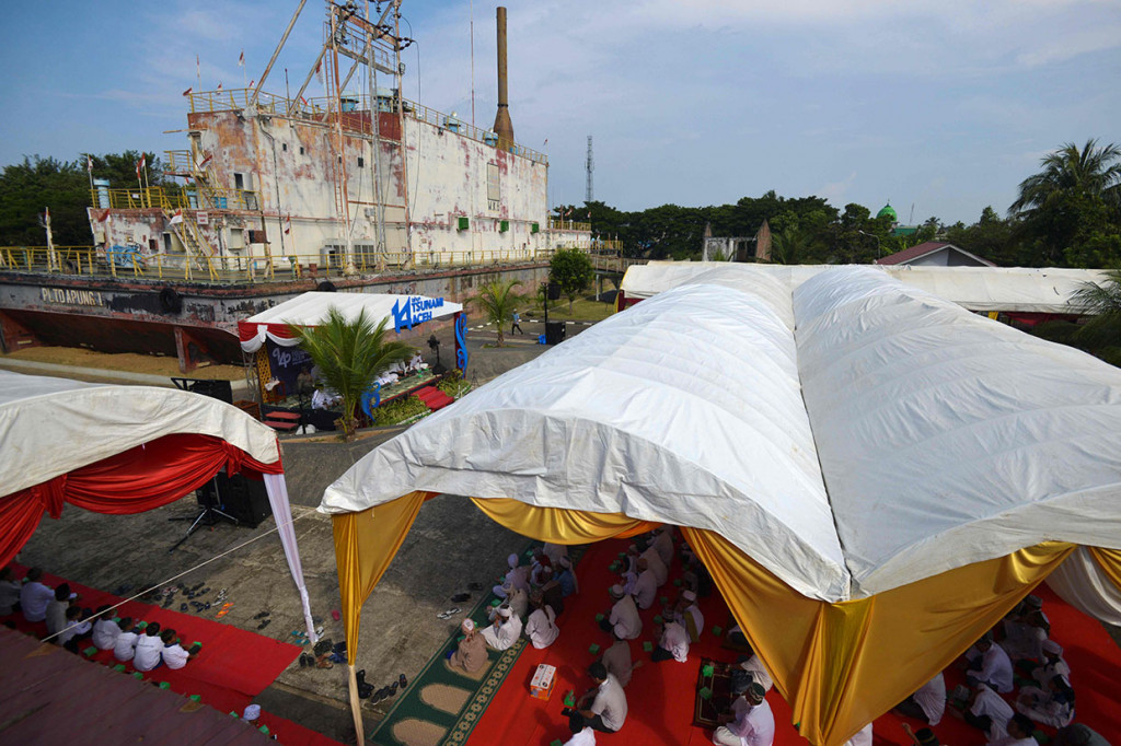 Warga melakukan zikir dan doa bersama memperingati 14 tahun bencana gempa dan tsunami Aceh di situs tsunami PLTD Apung di Desa Punge, Blang Cut, Jaya Baru, Banda Aceh. AFP/Chaideer Mahyuddin