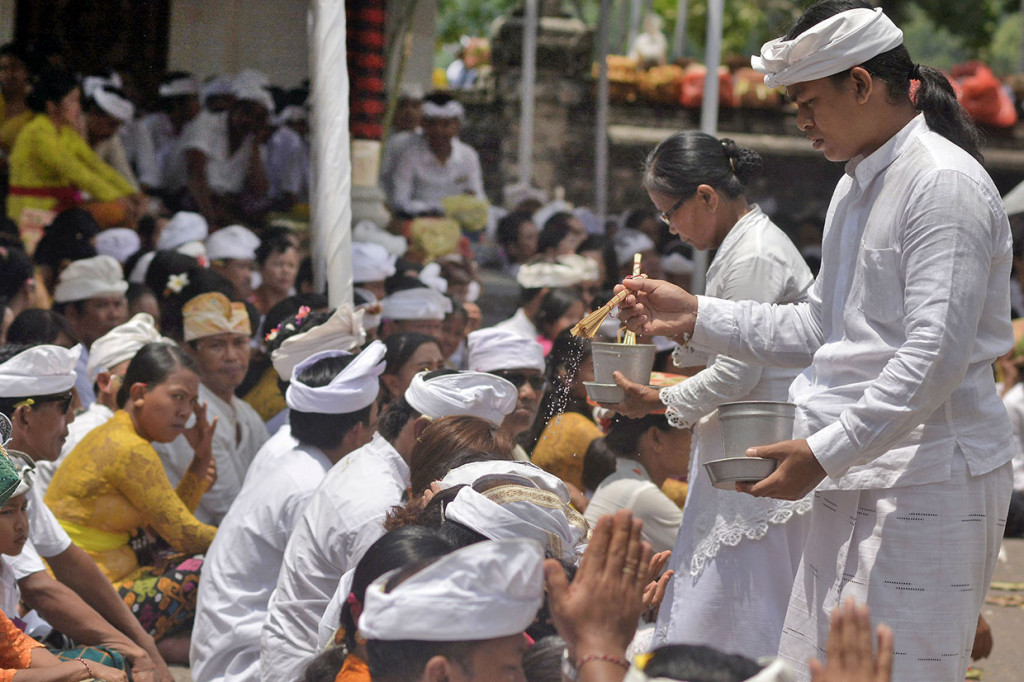 Pemuka agama Hindu memercikkan air suci saat persembahyangan Hari Raya Kuningan di Pura Sakenan, Denpasar, Bali, Sabtu, 5 Januari 2019.