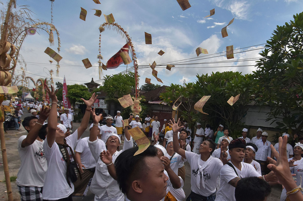 Warga saling berebut menangkap uang yang dilemparkan warga lainnya dalam tradisi Mesuryak di Desa Bongan Gede, Tabanan. 