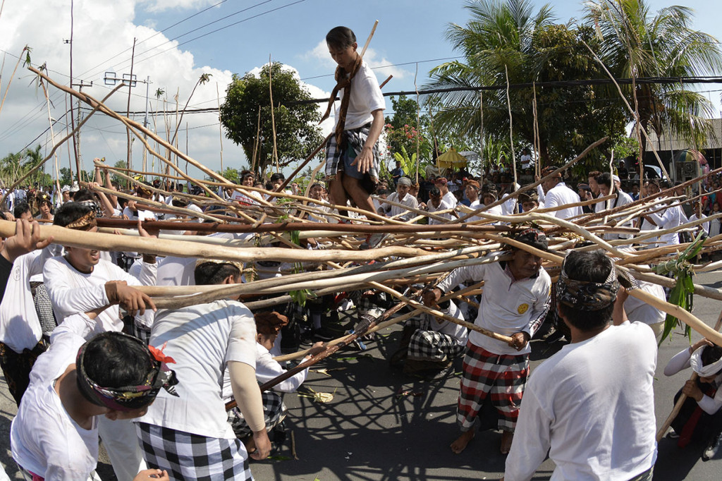 Seorang pemuda berdiri di atas tongkat yang disatukan warga saat Tradisi Mekotek di Desa Munggu, Badung, Bali.
