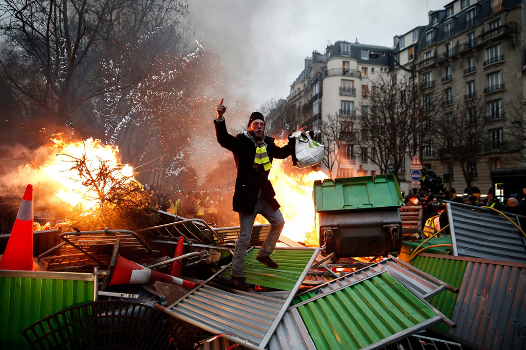 Seorang pengunjuk rasa berdiri di atas sejumlah tempat sampah yang dibakar di Paris, Prancis. Afp Photo/Abdul Abeissa
