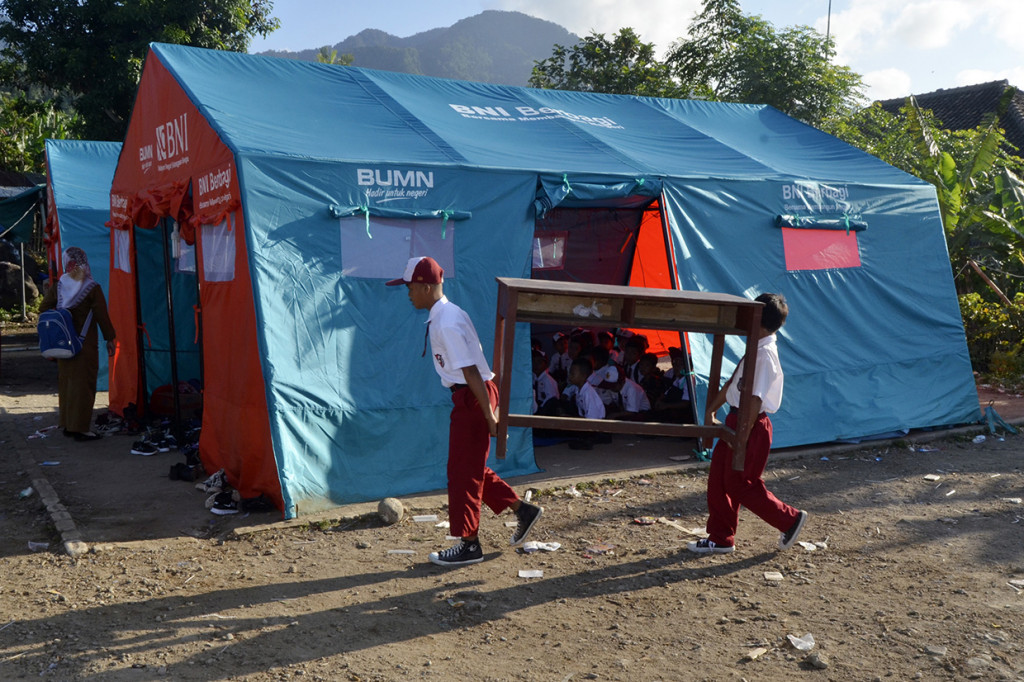 Sejumlah siswa SD Yayasan Madrasah Ibtidaiyah (MI) Darussalam Sukaraja mengangkat meja dan kursi dari sekolah mereka menuju tenda darurat untuk kegiatan belajar mengajar di Desa Sukaraja, Kabupaten Lampung Selatan, Lampung.
