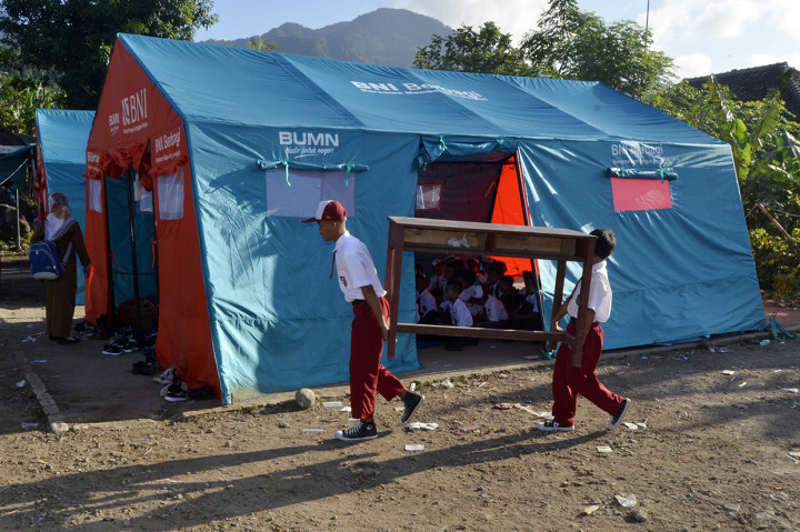 Sejumlah siswa SD Yayasan Madrasah Ibtidaiyah (MI) Darussalam Sukaraja mengangkat meja dan kursi dari sekolah mereka menuju tenda darurat untuk kegiatan belajar mengajar di Desa Sukaraja, Kabupaten Lampung Selatan, Lampung.
