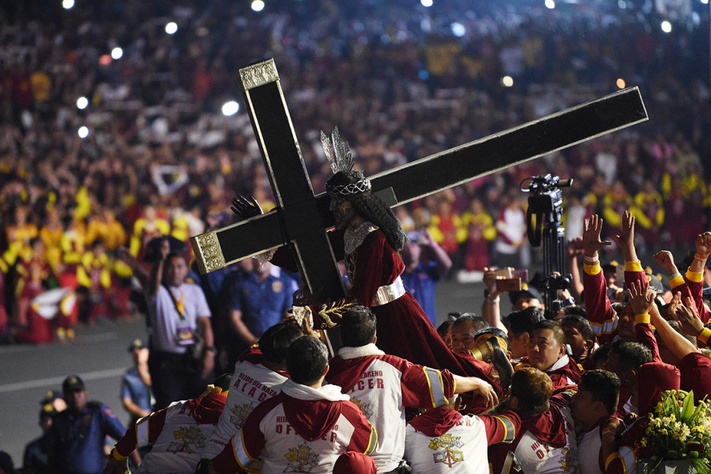 Patung Yesus tersebut dipindahkan dengan cara ditempatkan di atas sebuah kendaraan dan ditarik tali juga didorong dari belakang. Para jemaah pun berlomba menyentuh setiap bagian dari kendaraan Black Nazarene. Afp Photo/Ted Aljibe

