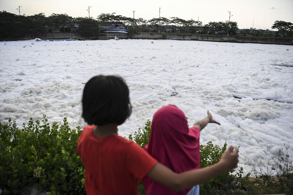 Dua orang anak melihat air Kanal Banjir Timur yang berbusa di kawasan Marunda, Jakarta.