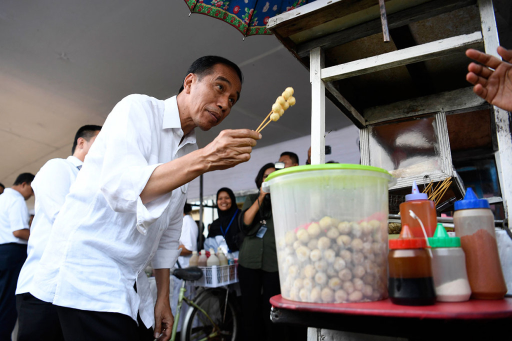 Presiden Joko Widodo membeli jajanan cilok saat meninjau usaha nasabah program pinjaman Membina Ekonomi Keluarga Sejahtera (Mekaar) binaan PNM di lapangan Sepak Bola Gongseng, Ciracas, Jakarta Timur, Kamis, 10 Jakarta 2019.