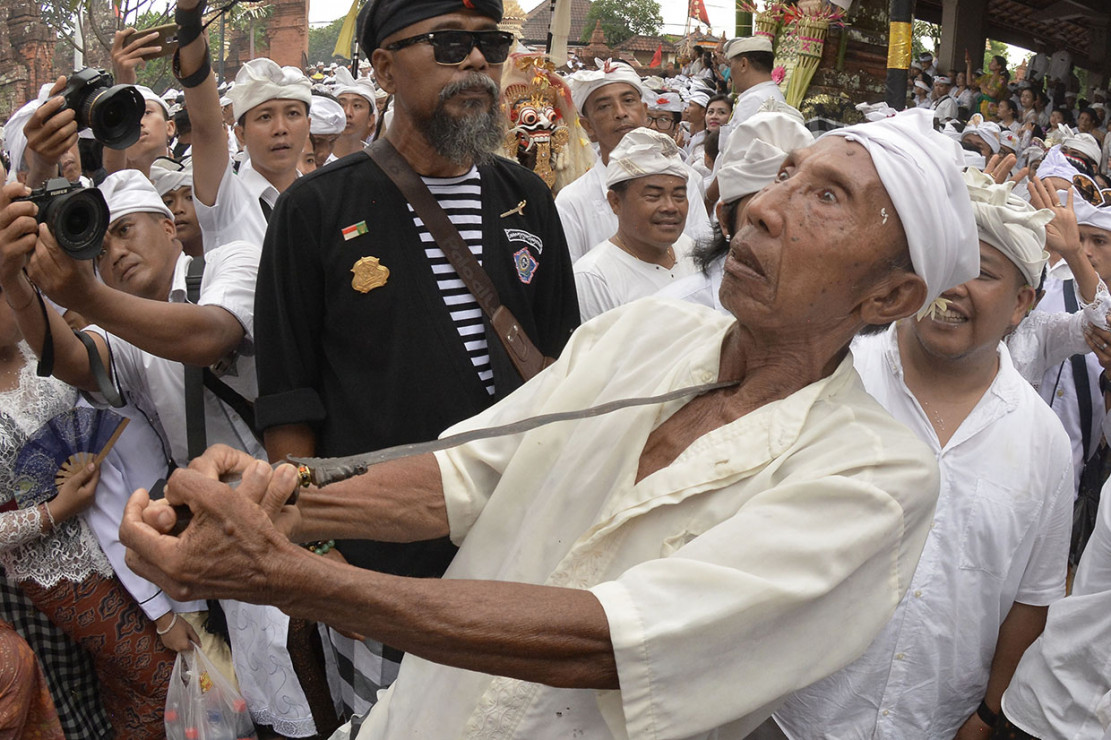 Seorang pria Bali yang menusukkan keris ke tubuhnya saat Ngerebong | Sumber: Medcom.id
