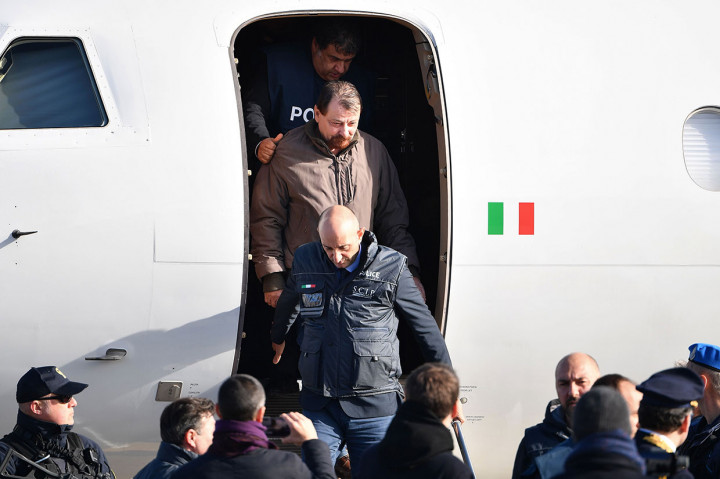 Mantan militan komunis Italia Cesare Battisti (tengah) dikawal petugas kepolisian turun dari pesawat setelah tiba di Bandara Ciampino di Roma, Senin, 14 Januari 2019 waktu setempat.