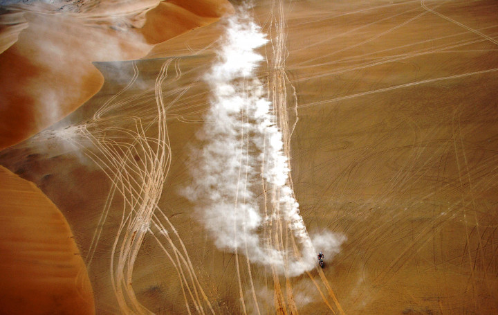 Seorang pereli sepeda motor melintasi jalur yang penuh jejak ban saling potong dari peserta sebelumnya. 