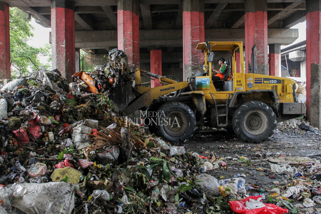 Alat berat dikerahkan untuk membersih sampah yang menumpuk di kolong tol Wiyoto-Wiyono, Sungai Bambu, Tanjung Priok, Jakarta. 