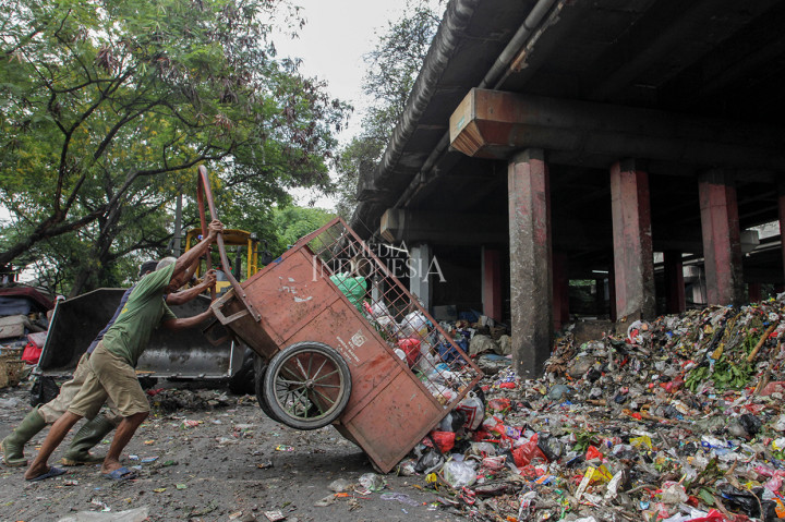 Petugas kebersihan membuang sampah di kolong tol Wiyoto-Wiyono, Sungai Bambu, Tanjung Priok, Jakarta.