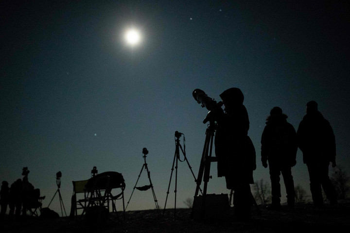 Warga melihat fenomena terjadinya super blood wolf moon dengan teleskop di Wina, Austria. AFP Photo/Georg Hochmuth
