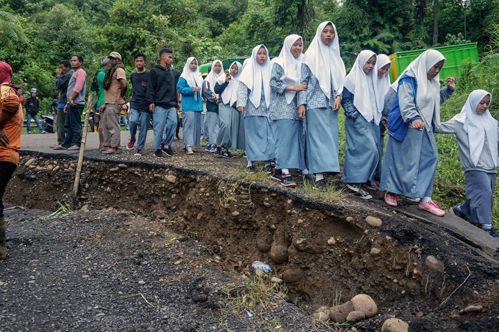 Sejumlah pelajar terpaksa berjalan kaki untuk kemudian berganti kendaraan menuju sekolah saat melewati jalan yang ambles di Desa Tenogo, Paninggaran, Kabupaten Pekalongan, Jawa Tengah.