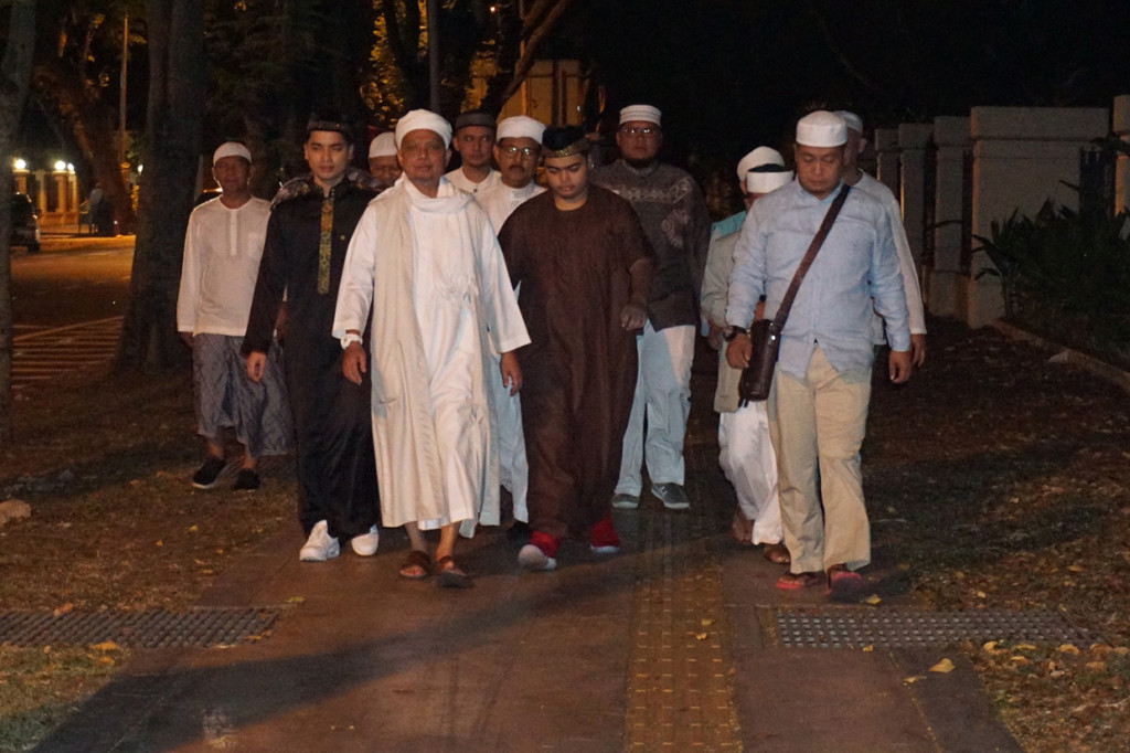 Pimpinan Majelis Taklim Adz-Dzikra KH Muhammad Arifin Ilham dengan didampingi putranya Muhammad Amer Azzikra (gamis coklat muda) dan Muhammad Alvin Faiz (gamis coklat tua) bersama para jamaah berjalan kaki dari Apartemen Mansion One ke Masjid Jamik Al-Munawar Kelawai di George Town, Penang, Malaysia, untuk sholat subuh sejauh 600 meter dari apartemennya. 