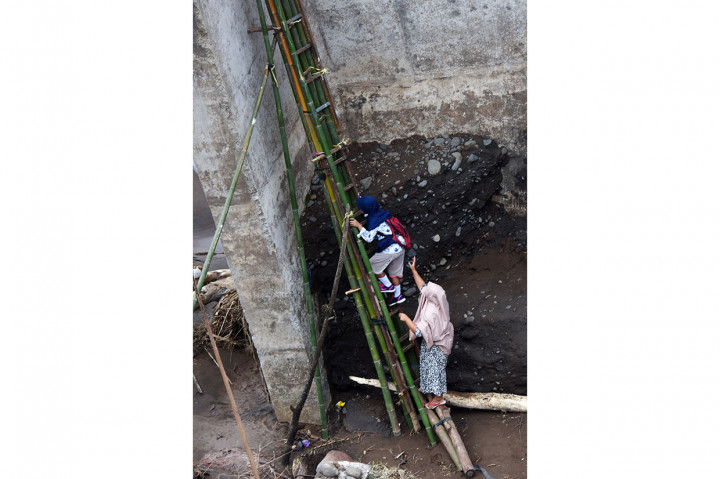 Sejumlah warga bersama anaknya berusaha naik tangga darurat saat akan menyeberang jembatan Manuju yang ambruk di Desa Moncongloe, Manuju, Gowa, Sulawesi Selatan, Rabu, 30 Januari 2019. 