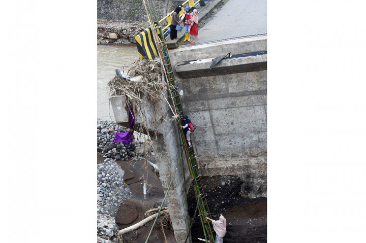 Warga terpaksa membuat tangga darurat untuk menyeberangi jembatan yang ambruk terseret arus sungai Jeneberang Gowa pada 22 Januari lalu.