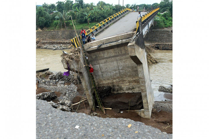 Warga terpaksa menyeberang jembatan yang telah ambruk tersebut untuk mempersingkat jarak dan waktu.