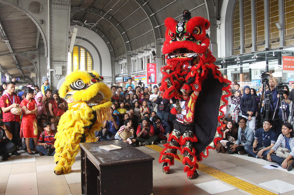 Atraksi Barongsai menghibur penumpang kereta commuter line di Stasiun Jakarta Kota, Jakarta.