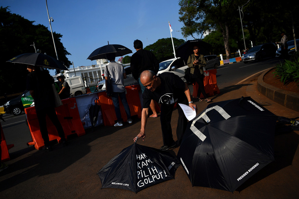 Massa juga juga memegang payung bertuliskan 'Hak Kami Pilih Golput'.