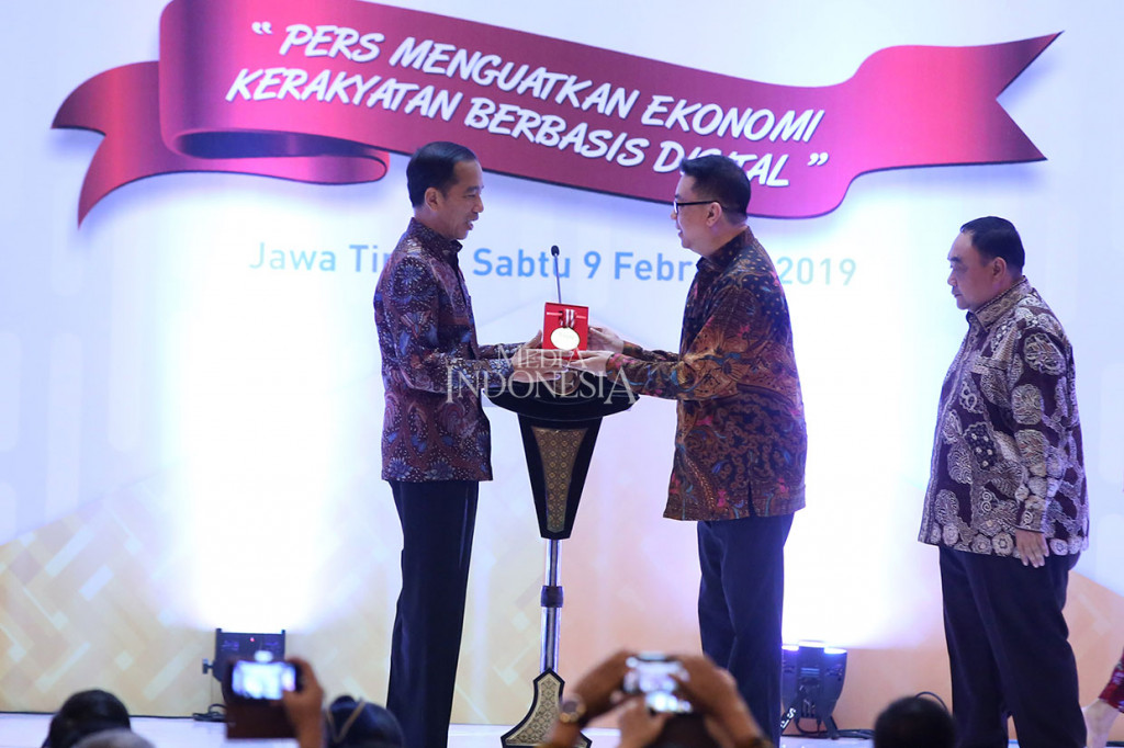 Presiden Joko Widodo menerima plakat Penghargaan Kemerdekaan Pers yang diberikan Ketua Dewan Pers Yosep Adi Prsetyo (tengah) disaksikan Penanggung Jawab HPN 2019 Margiono (kanan) pada Puncak Peringatan Hari Pers Nasional 2019 di Surabaya, Jawa Timur, Sabtu, 9 Februari 2019. 