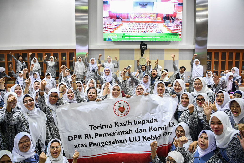 Puluhan bidan meluapkan kegembiraan saat menonton pengesahaan UU tentang Kebidanan pada rapat paripurna DPR dari ruang rapat Komisi IX DPR di Kompleks Parlemen, Senayan, Jakarta.