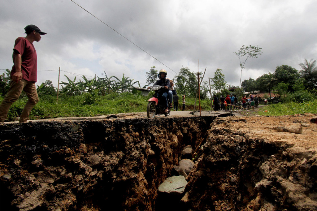 Sepeda motor melintas di jalan yang terbelah akibat pergerakan tanah di jalur wisata, Karang Tengah, Sentul, Kabupaten Bogor, Jawa Barat, Sabtu, 16 Februari 2019. 