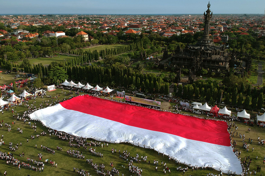 Pelajar membentangkan bendera merah putih saat kegiatan Millennial Road Safety Festival yang diseleggarakan Polda Bali di Lapangan Niti Mandala Renon, Denpasar, Bali.