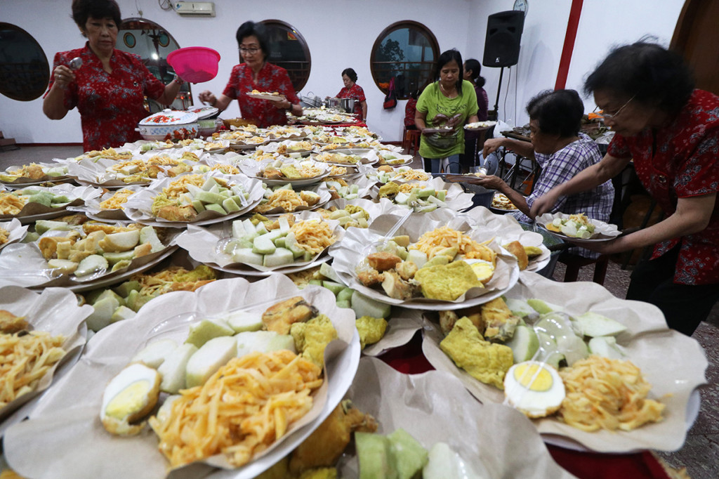 Warga Tionghoa menyiapkan lontong beserta lauk pauknya ke dalam piring di Kelenteng Tjoe Hwie Kiong di Kota Kediri, Jawa Timur. Sebanyak 1.100 lontong disajikan untuk dimakan bersama saat merayakan Cap Go Meh sebagai rangkaian penutupan perayaan Tahun Baru Imlek. Antara Foto/Prasetia Fauzani