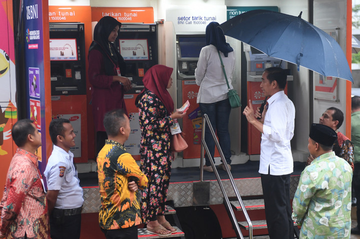 Presiden Joko Widodo (kanan) berdialog dengan warga yang baru mencairkan bantuannya melalui ATM BNI dalam acara penyaluran bantuan sosial Program Keluarga Harapan (PKH) dan Bantuan Pangan Non Tunai (BPNT) tahun 2019 di Cibinong, Bogor.