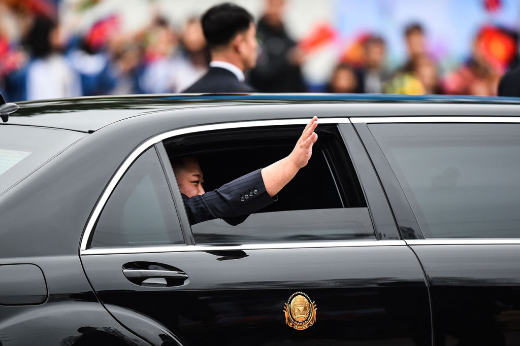 Jong Un melambaikan tangan dari dalam mobil kepada para penduduk yang berbaris di pinggir jalan saat akan menuju Hanoi, sekitar 170 km dari Dong Dang.