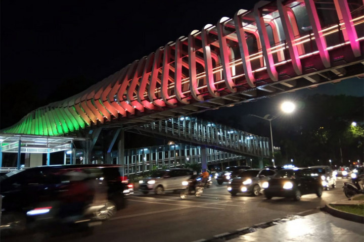 Kendaraan melintas di bawah Jembatan Penyeberangan Orang (JPO) Gelora Bung Karno, Senayan, Jakarta, yang dihiasi lampu warna-warni, Selasa, 26 Februari 2019.