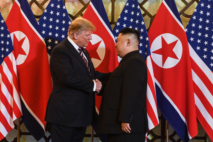 Trump dan Kim saling berjabat tangan lalu berpose bersama di depan deretan bendera nasional AS-Korut.