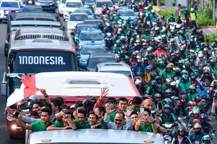 Pemain dan ofisial Timnas U-22 Indonesia menaiki bus tingkat ketika mengikuti konvoi menuju Istana Negara saat melintas di Jalan Sudirman, Jakarta, Kamis, 28 Februari 2019.