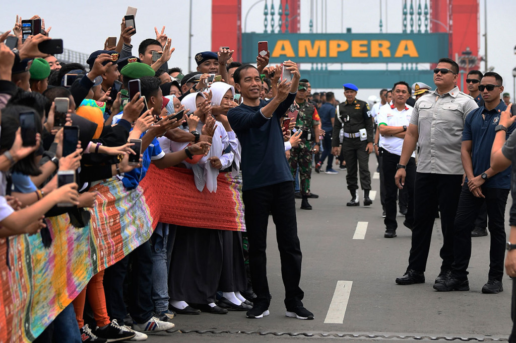 Presiden Joko Widodo melayani permintaan swafoto bersama warga, di sela upaya pemecahan rekor Muri pembentangan kain jumputan sepanjang 1,177 Km, di Jembatan Ampera, Palembang, Sumsel, Sabtu, 9 Maret 2019.