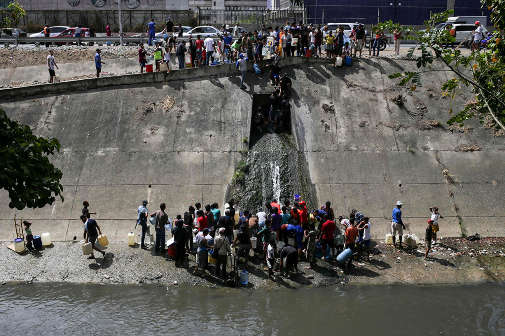 Kondisi tak ada listrik selama lima hari menyebabkan warga Venezuela kesulitan air. Mereka terpaksa berbondong-bondong mencari air di saluran pembuangan. Afp Photo/Crstian Hernandez