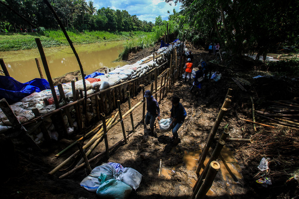 Warga menyelesaikan pembuatan tanggul darurat di bantaran Sungai Serang, Bendungan Wates, Kulon Progo, guna mengantisipasi terjadinya banjir susulan akibat jebolnya tanggul. 