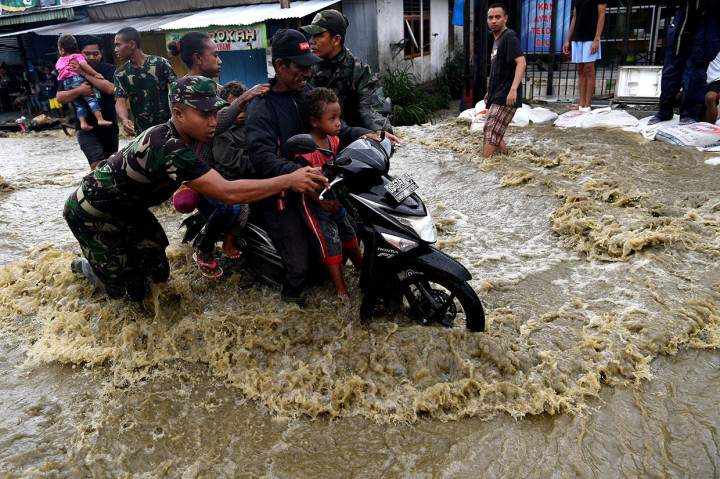 Prajurit TNI membantu seorang pengendara ketika berusaha menerobos banjir di Sentani, Jayapura, Papua.
